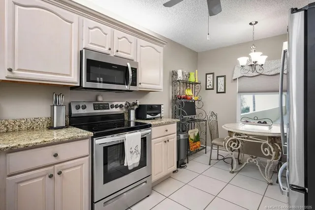 a kitchen with stainless steel appliances granite countertop a stove top oven a sink dishwasher and white cabinets with wooden floor