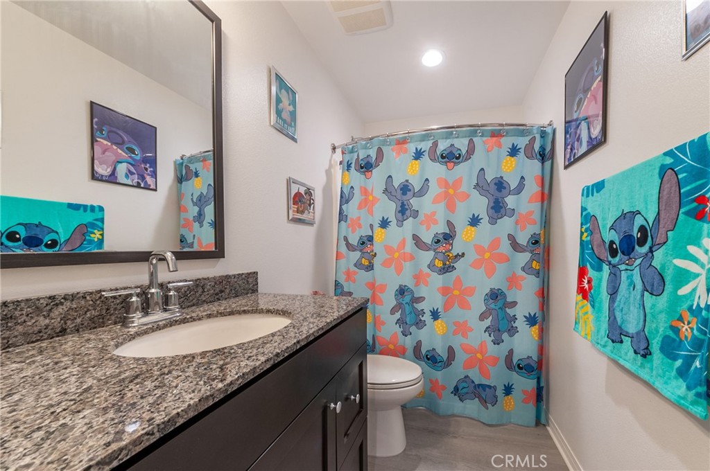 27283 Chase Road Menifee, CA 92584 - Photo 13 of 16 a bathroom with a granite countertop sink a toilet and a shower curtain