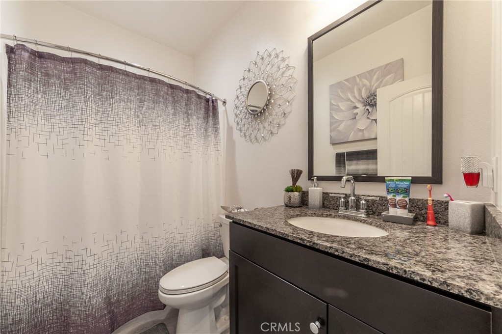27283 Chase Road Menifee, CA 92584 - Photo 8 of 16 a bathroom with a granite countertop sink a toilet and a mirror
