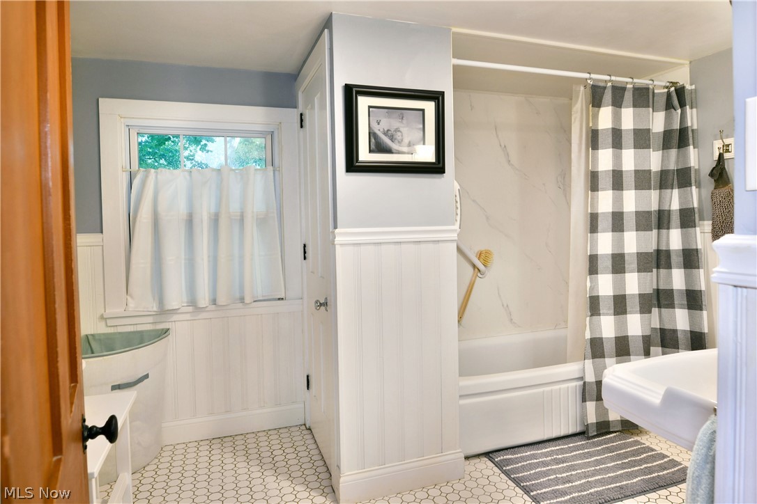 8683 King Graves Road Northeast Warren, OH 44484 - Photo 35 of 50 Bathroom featuring a bathtub with a marble-patterned surround, white beadboard paneling, and hexagonal floor tiling