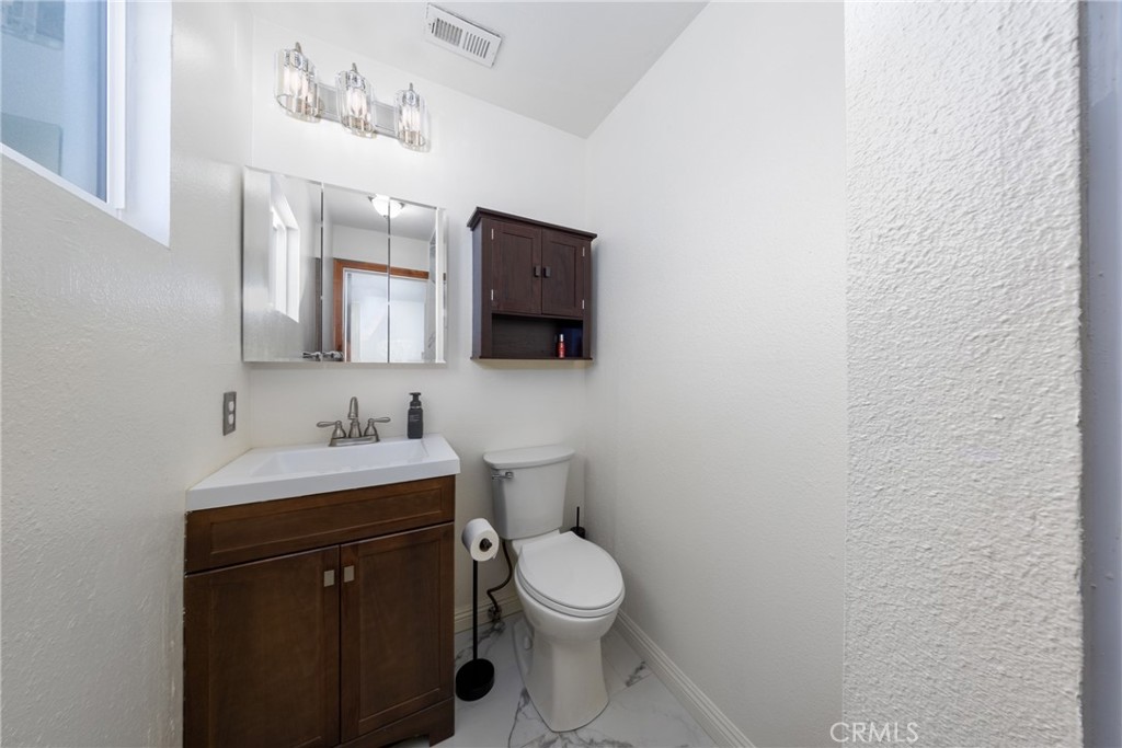 10514 Cameo Court Riverside, CA 92505 - Photo 22 of 30 a bathroom with a toilet a sink a mirror and vanity