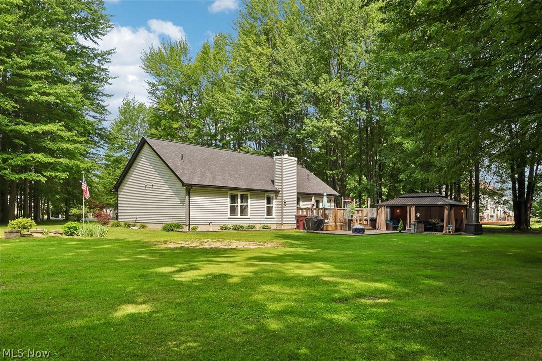 3213 Bates Road Madison, OH 44057 - Photo 40 of 45 Expansive backyard featuring a lush lawn, mature trees, a multi-level wood deck, a built-in hot tub, and a covered gazebo