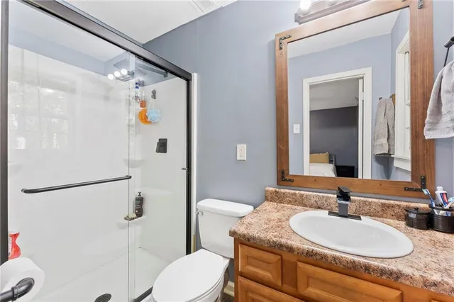 a bathroom with a granite countertop sink a mirror a toilet and shower