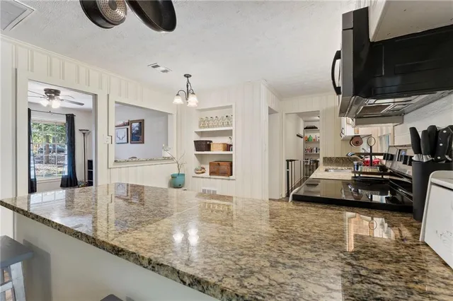 a kitchen with granite countertop a sink a counter top space cabinets and stainless steel appliances
