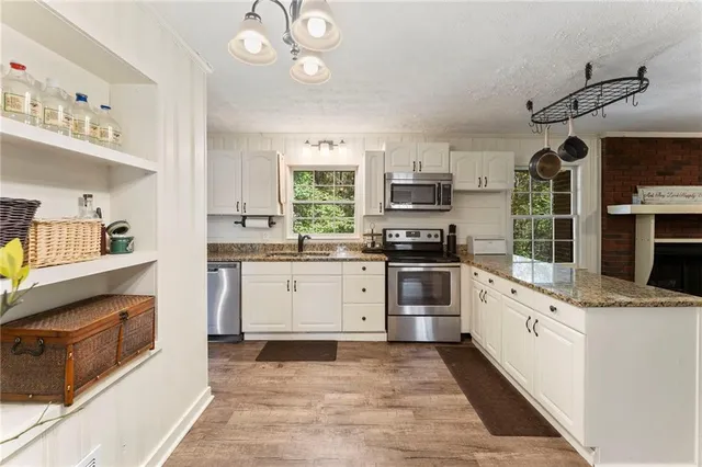 a kitchen with granite countertop a stove top oven sink and cabinets
