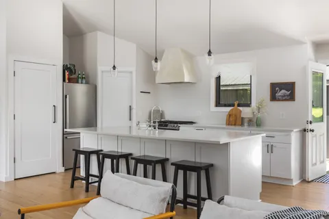 a kitchen with stainless steel appliances granite countertop a kitchen island hardwood floor sink and stove