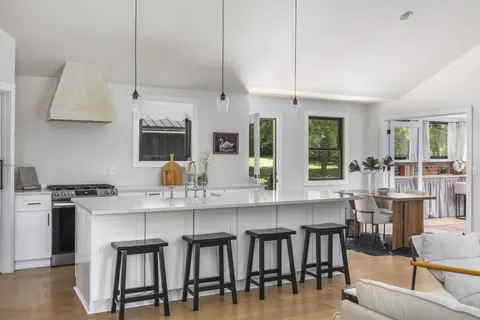 a kitchen with a table chairs stove and white cabinets