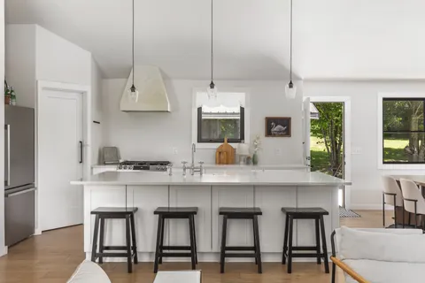 a kitchen with stainless steel appliances a sink a stove a refrigerator and white cabinets with wooden floor