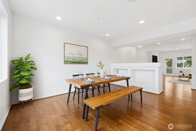 a kitchen with stainless steel appliances granite countertop a refrigerator a stove top oven a sink dishwasher a dining table and chairs with wooden floor