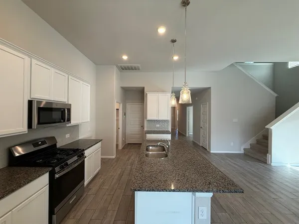 a kitchen with stainless steel appliances granite countertop a sink a stove top oven a counter space and cabinets