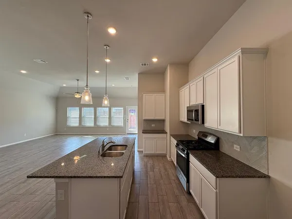 a kitchen with kitchen island stainless steel appliances a sink stove and cabinets