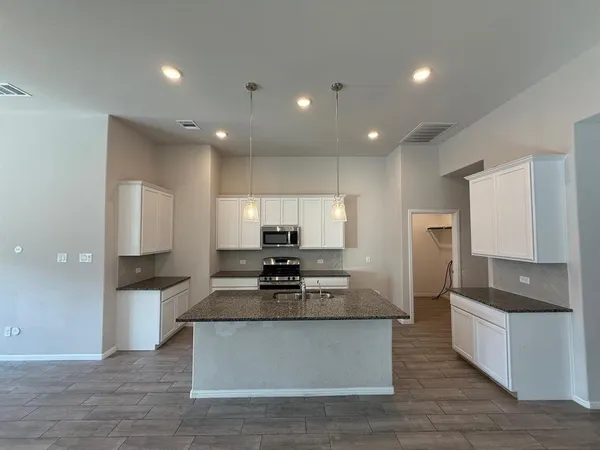 a large kitchen with stainless steel appliances granite countertop a stove a sink a refrigerator and a granite counter tops with wooden floors