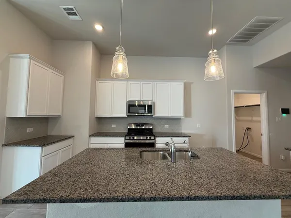 a kitchen with kitchen island granite countertop a sink a stove and cabinets