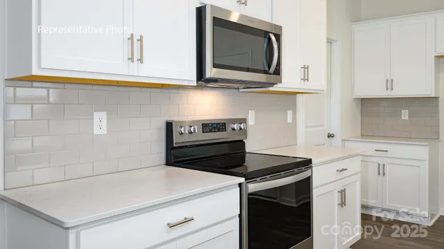 a kitchen with white cabinets and black appliances