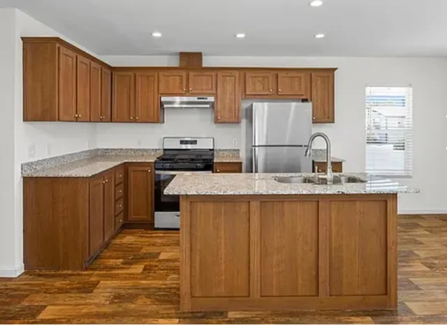 a kitchen with kitchen island granite countertop wooden cabinets and refrigerator