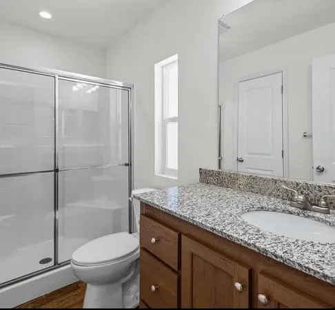 a bathroom with a granite countertop sink toilet and shower