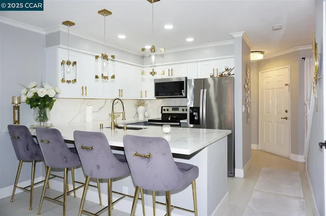 a large kitchen with kitchen island a dining table chairs stainless steel appliances and cabinets