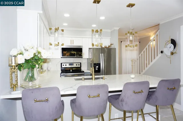 a kitchen with stainless steel appliances granite countertop a dining table chairs microwave and sink