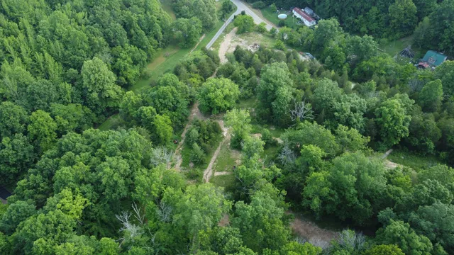 an aerial view of residential house with outdoor space and trees all around