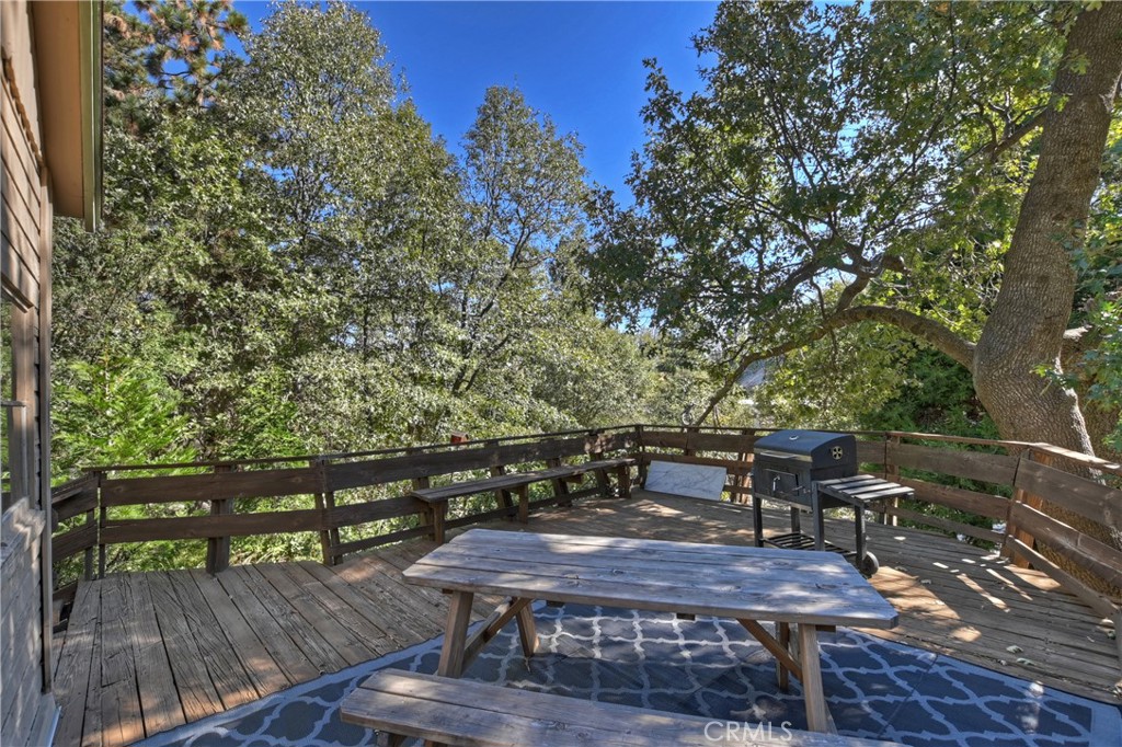 1262 Bear Springs Road Rimforest, CA 92378 - Photo 31 of 34 a view of a deck with table and chairs with wooden floor and fence