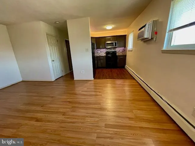a view of a living room with kitchen and wooden floor