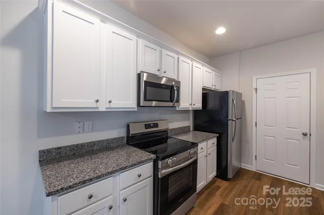 a kitchen with granite countertop a refrigerator stove and microwave