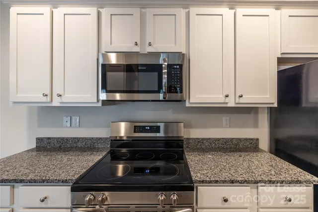 a kitchen with granite countertop white cabinets and stainless steel appliances