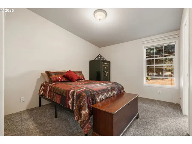 a bedroom with a bed a dresser and window