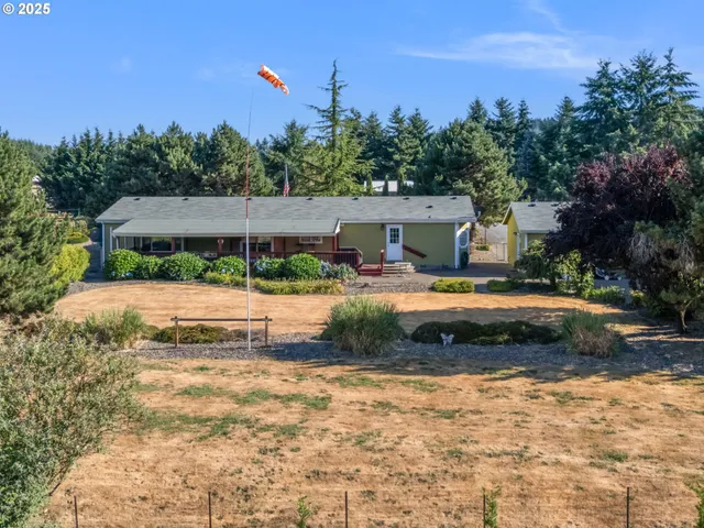a view of house with yard and trees in the background