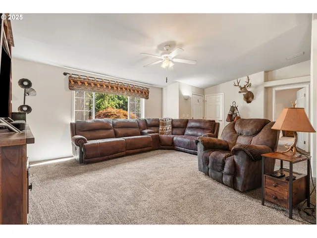 a living room with furniture a chandelier fan and a window