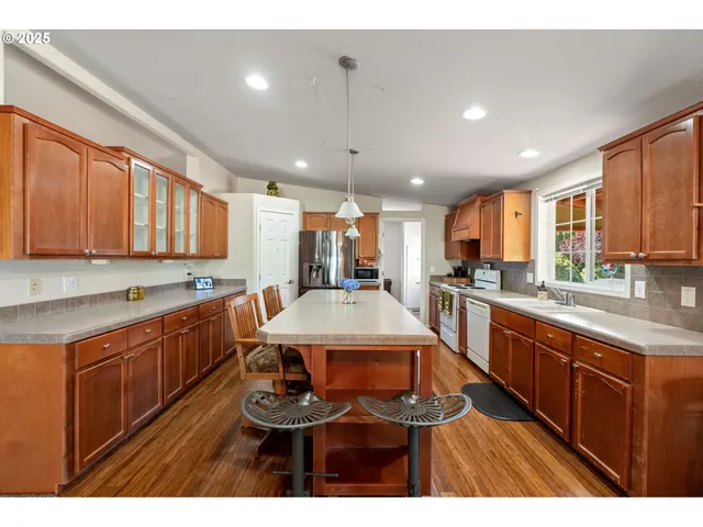 a kitchen with stainless steel appliances granite countertop a sink a stove a refrigerator cabinets and dining table