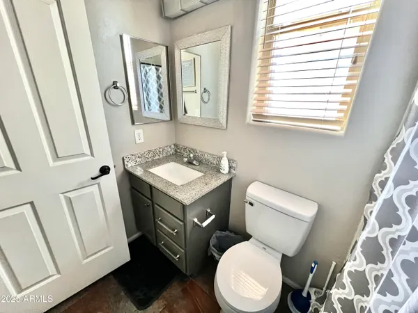 a bathroom with a toilet a sink a mirror a vanity and a window