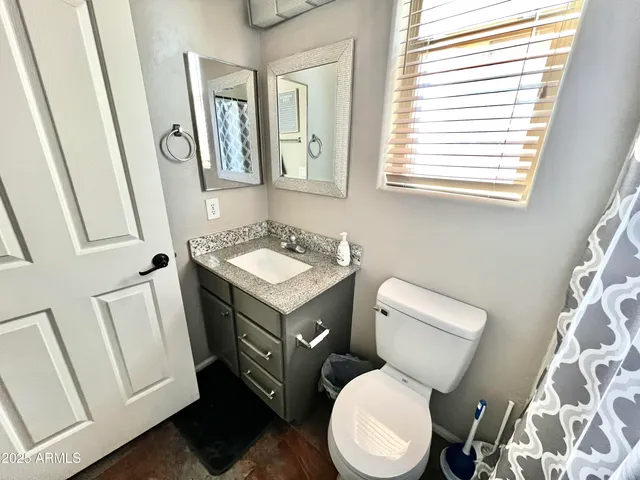 a bathroom with a toilet a sink a mirror a vanity and a window