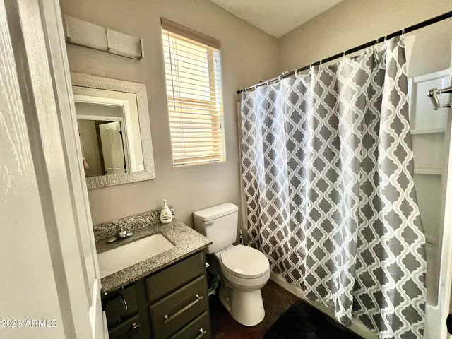 a bathroom with a granite countertop sink and a toilet