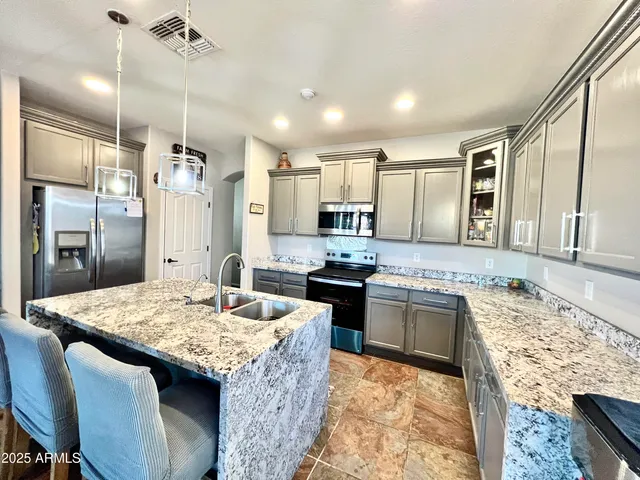 a kitchen with granite countertop kitchen island stainless steel appliances a sink stove and refrigerator
