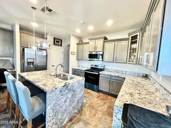 a large kitchen with kitchen island stainless steel appliances a stove refrigerator dining table and chairs