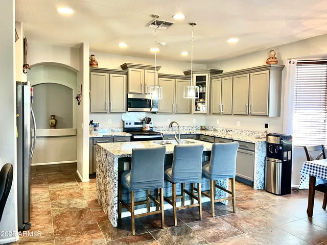 a kitchen with kitchen island granite countertop a sink counter top space appliances and cabinets