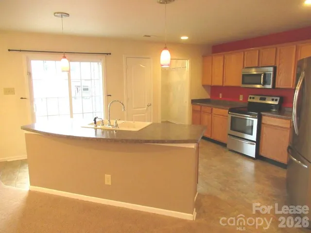 a kitchen with stainless steel appliances granite countertop a sink a stove top oven a counter space and cabinets