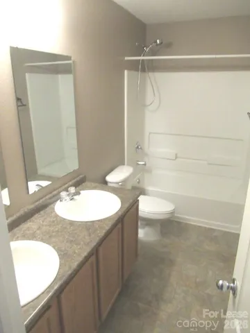 a bathroom with a granite countertop sink a toilet and a mirror