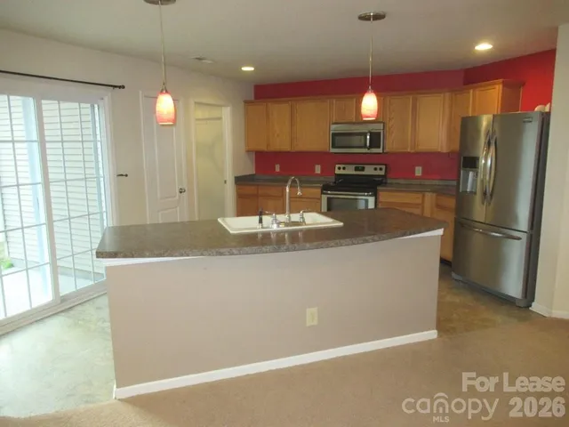 a kitchen with stainless steel appliances granite countertop a refrigerator a stove a sink and a microwave