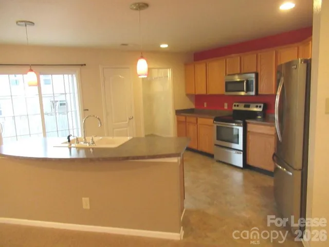 a kitchen with stainless steel appliances granite countertop a refrigerator a stove and a sink with wooden floor