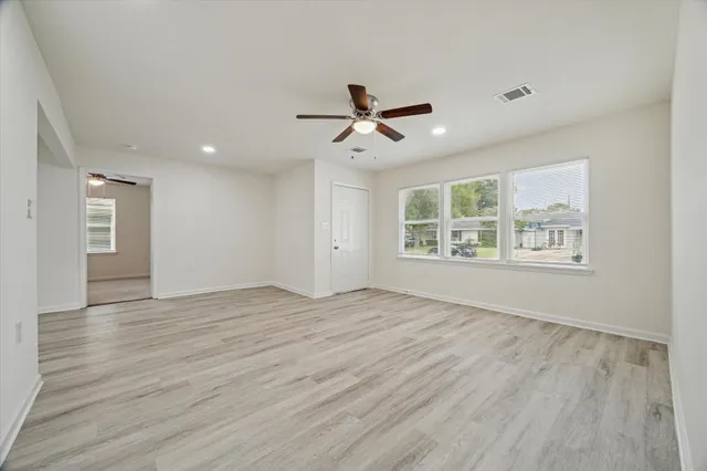a view of an empty room with a window and wooden floor