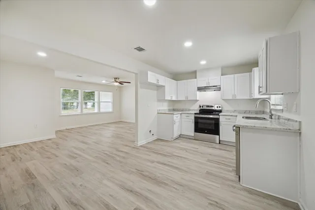 a kitchen with granite countertop a stove top oven sink and cabinets