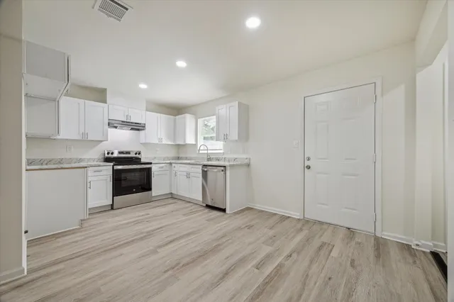 a kitchen with a white cabinets and wooden floor