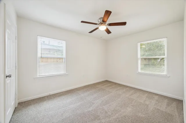 an empty room with a window and a ceiling fan