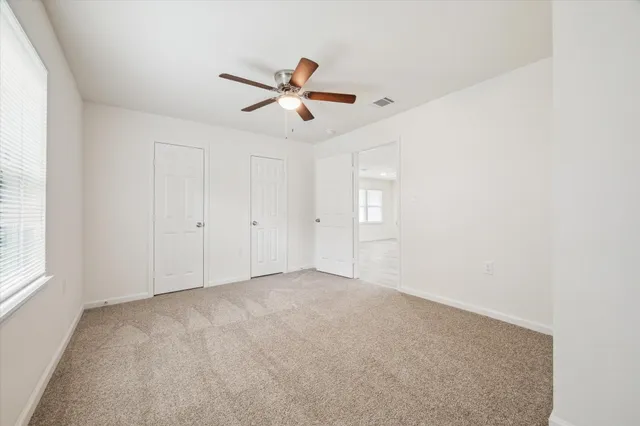 an empty room with windows and fan