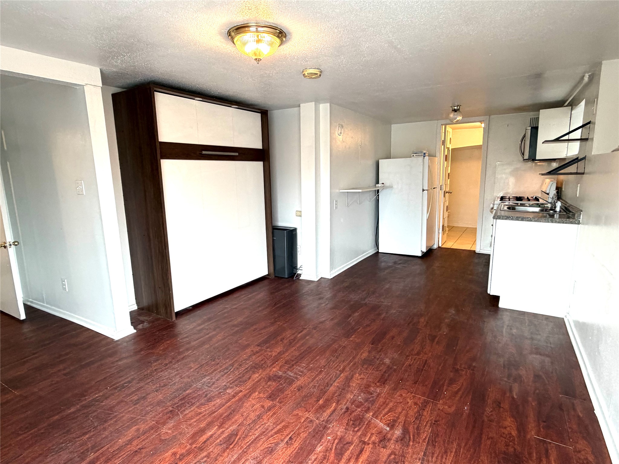 808 Edgecliff Terrace, Unit C Austin, TX 78704 - Photo 2 of 12 Kitchen featuring dark wood finished floors, a textured ceiling, freestanding refrigerator, white cabinetry, and gas stove