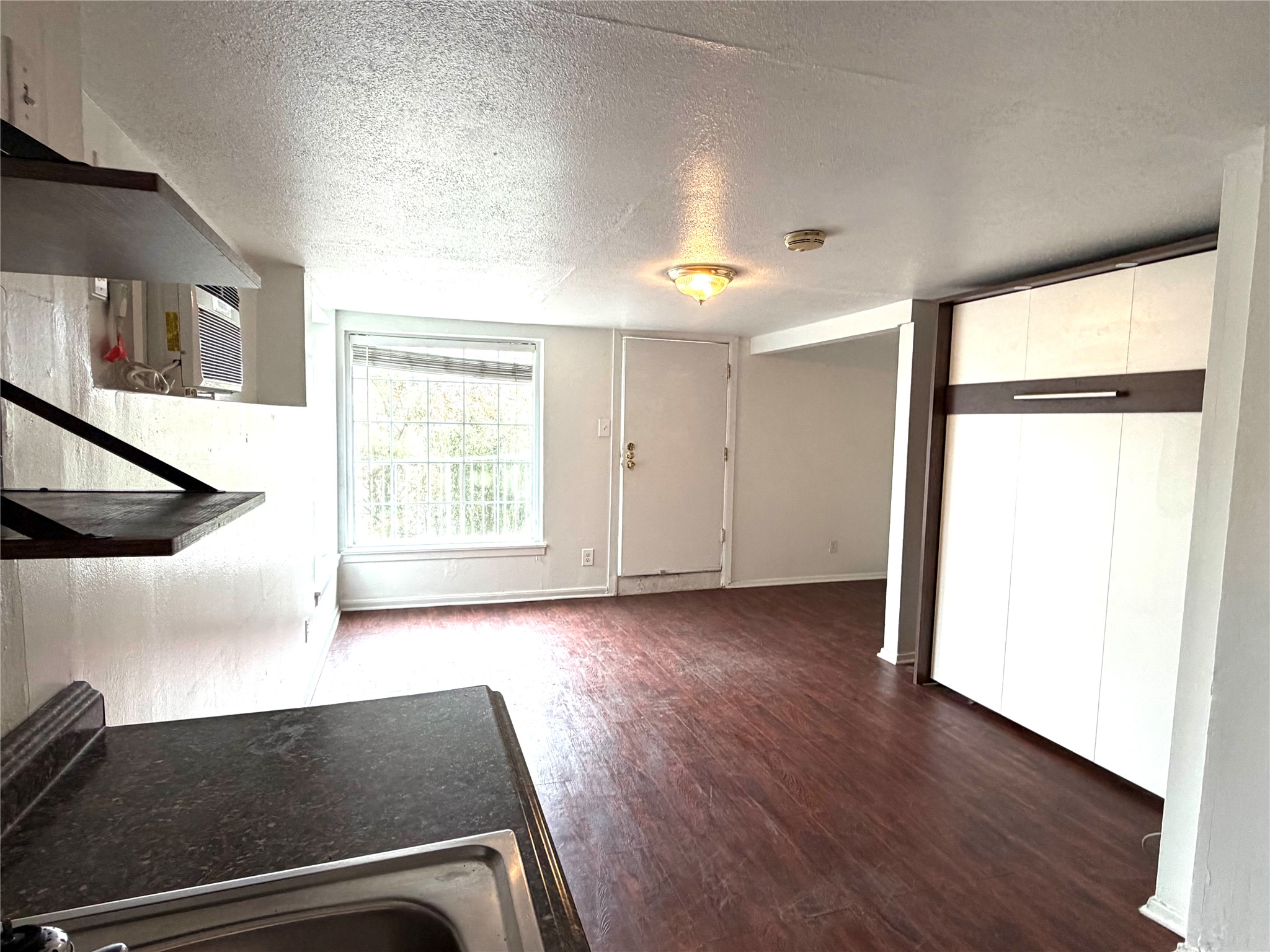 808 Edgecliff Terrace, Unit C Austin, TX 78704 - Photo 3 of 12 Kitchen featuring a textured ceiling, dark wood-style flooring, white cabinetry, and dark countertops