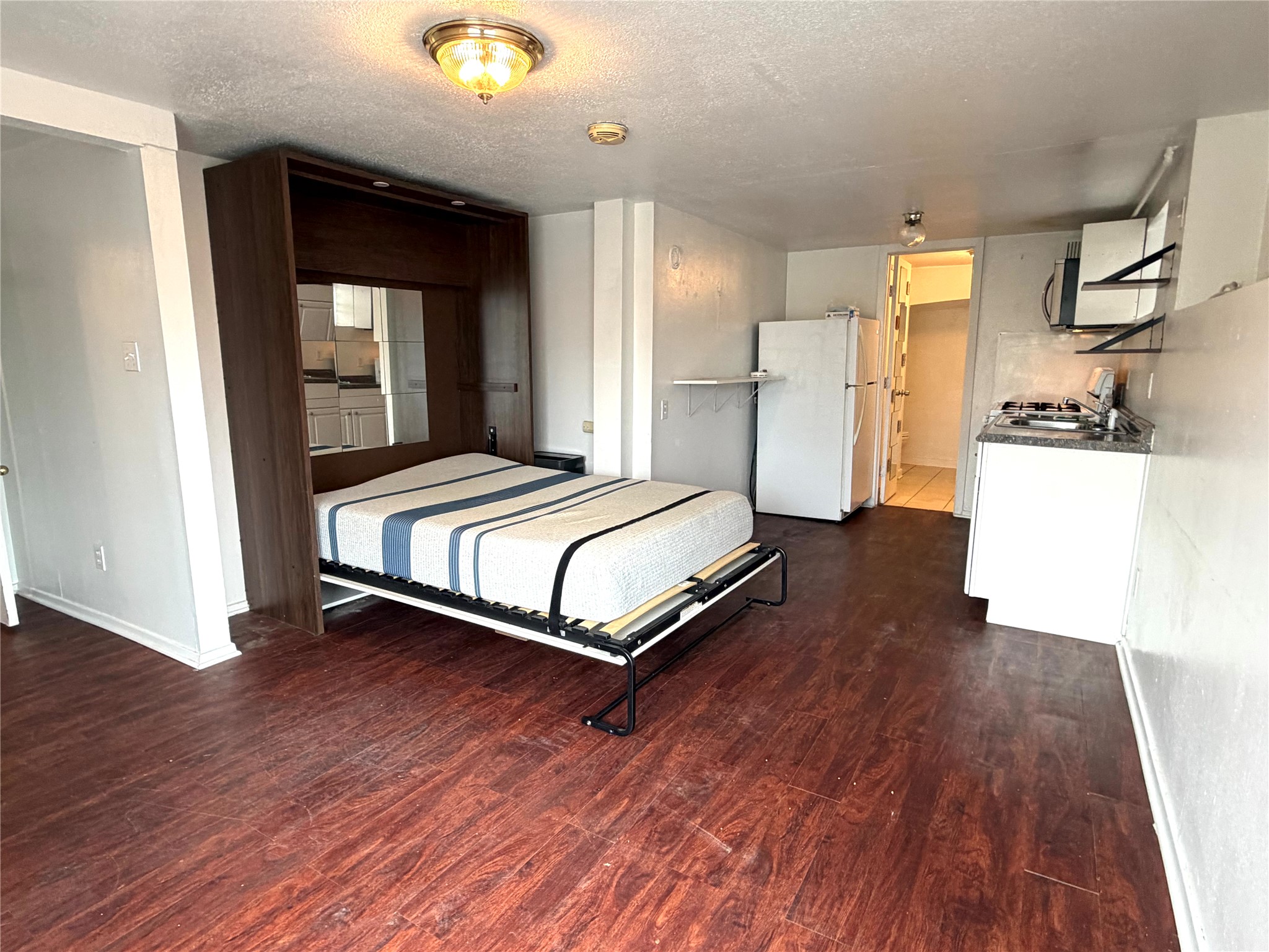808 Edgecliff Terrace, Unit C Austin, TX 78704 - Photo 4 of 12 Bedroom with dark wood-style flooring, freestanding refrigerator, and a textured ceiling
