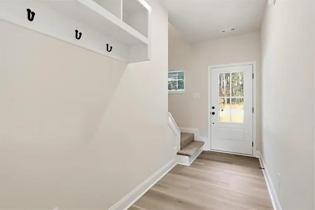 a view of an empty room with wooden floor and a window